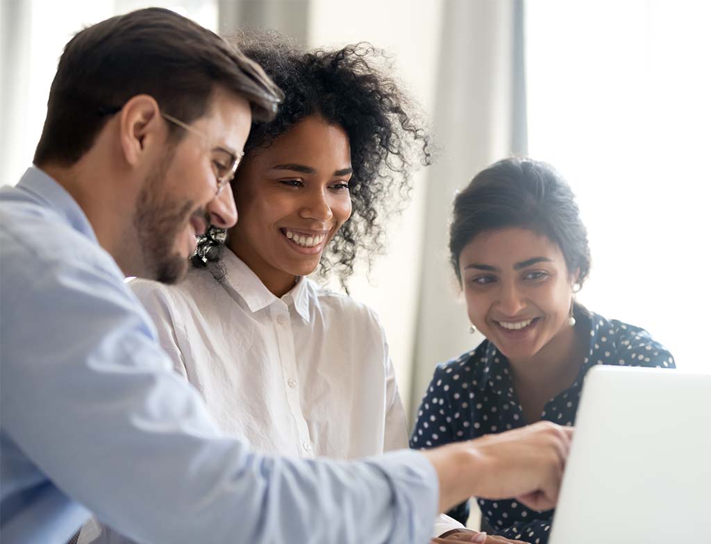 group smiling at laptop